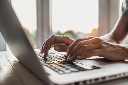 person typing on a laptop to create an html landing page